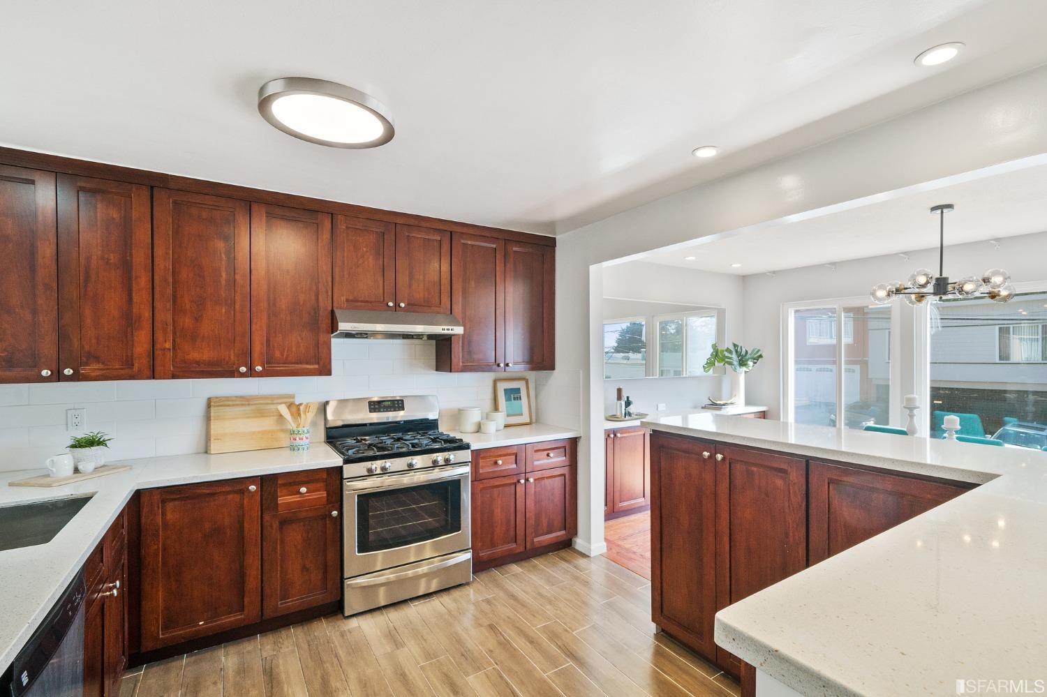 67 Marshall Way Daly City, CA 94014 - Photo 19 of 42 a kitchen with granite countertop wooden cabinets a stove a sink and dishwasher with wooden floor