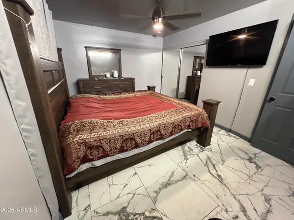 a bedroom with a bed a flat screen tv and a chandelier