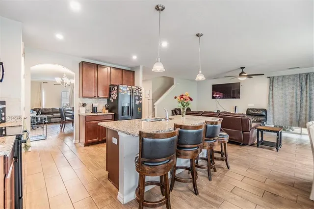 a dining hall with stainless steel appliances kitchen island granite countertop a dining table chairs and view living room