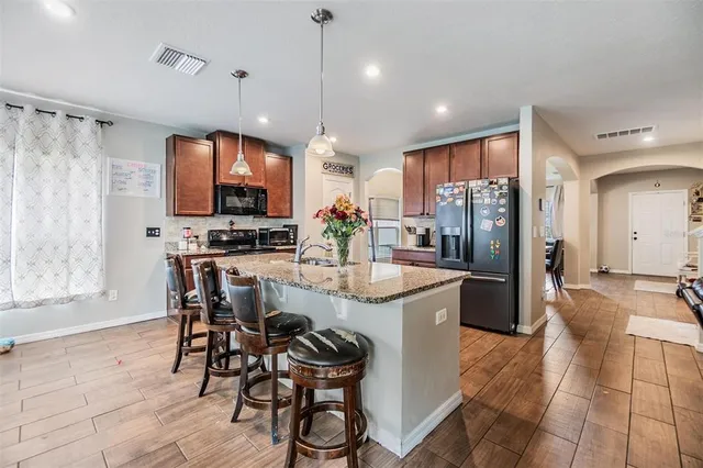 a kitchen with stainless steel appliances kitchen island granite countertop a sink refrigerator and microwave