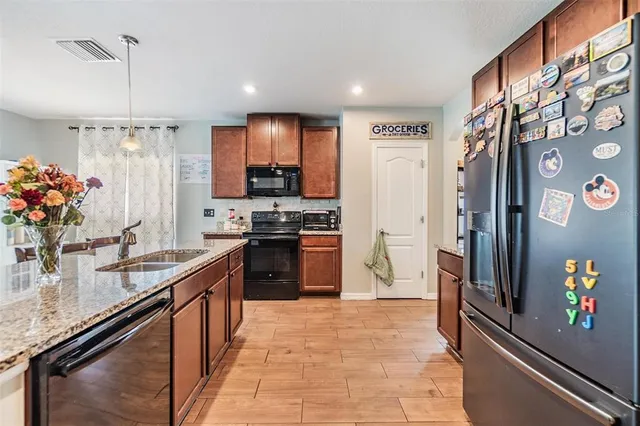 a kitchen with stainless steel appliances granite countertop a refrigerator a stove and a sink