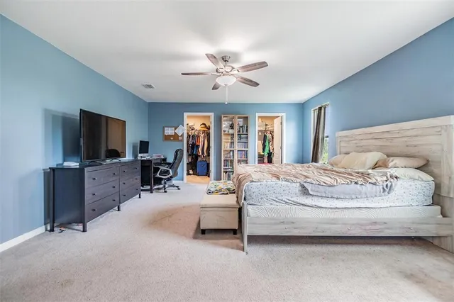 a spacious bedroom with a bed and a flat screen tv