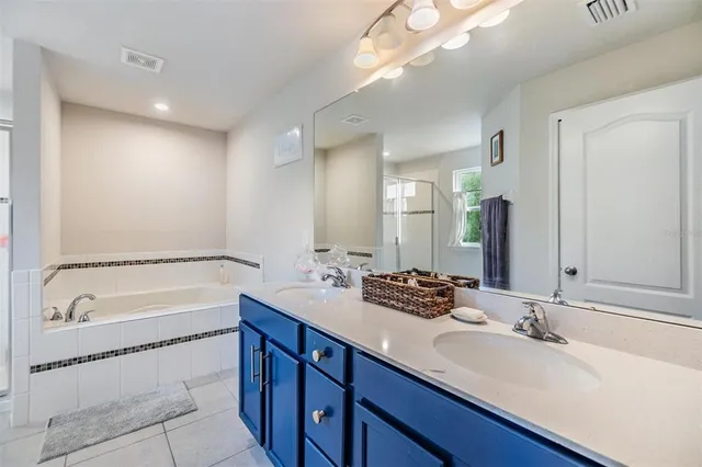 a bathroom with a double vanity sink and mirror with bathtub