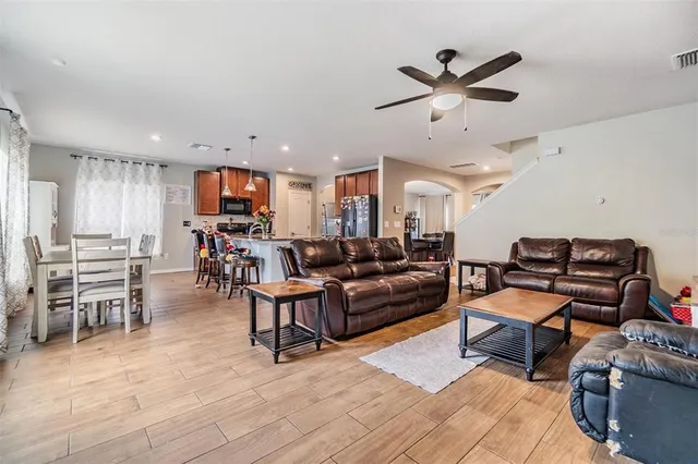 a living room with furniture kitchen view and a wooden floor