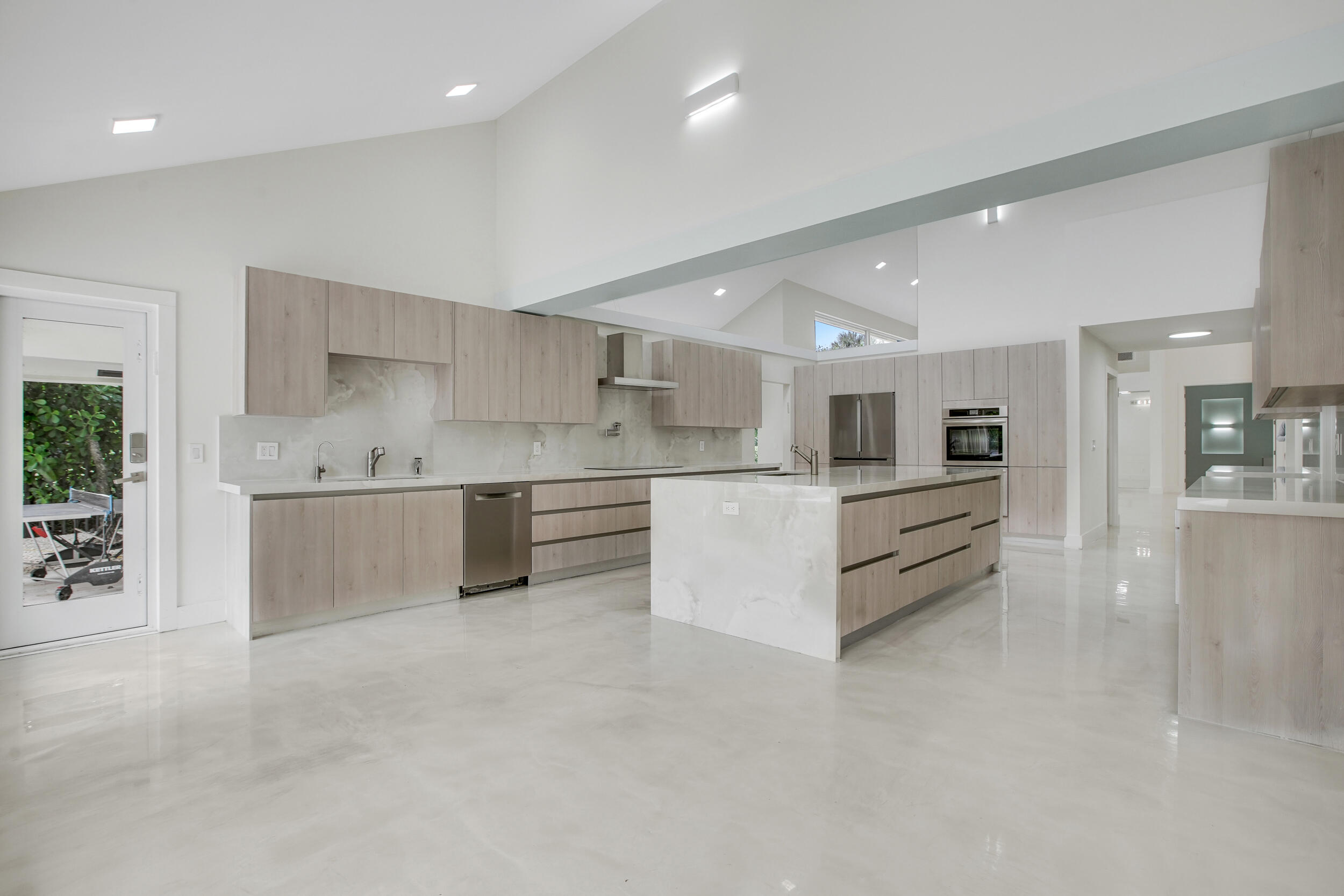 7351 Valencia Drive Boca Raton, FL 33433 - Photo 12 of 39 a large white kitchen with stainless steel appliances kitchen island a large counter top and a stove top oven