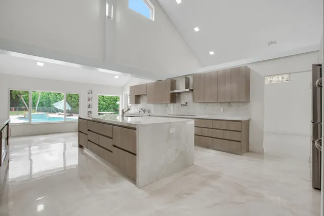 a kitchen with stainless steel appliances kitchen island granite countertop a refrigerator and a stove top oven