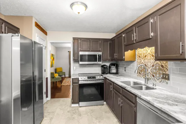 a kitchen with granite countertop a refrigerator stove and sink