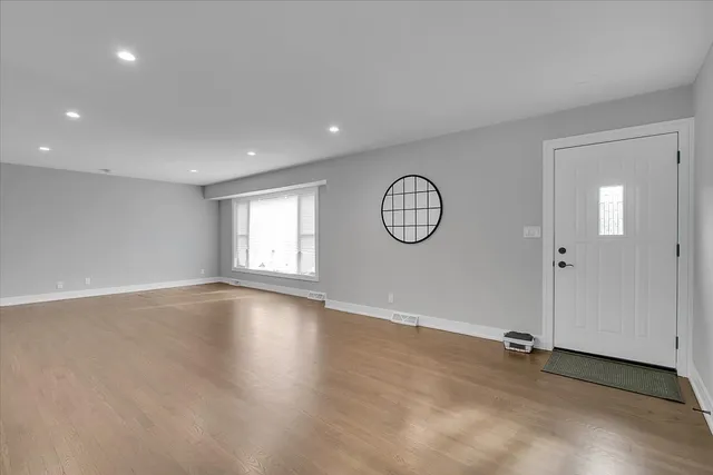 an empty room with wooden floor and mirror