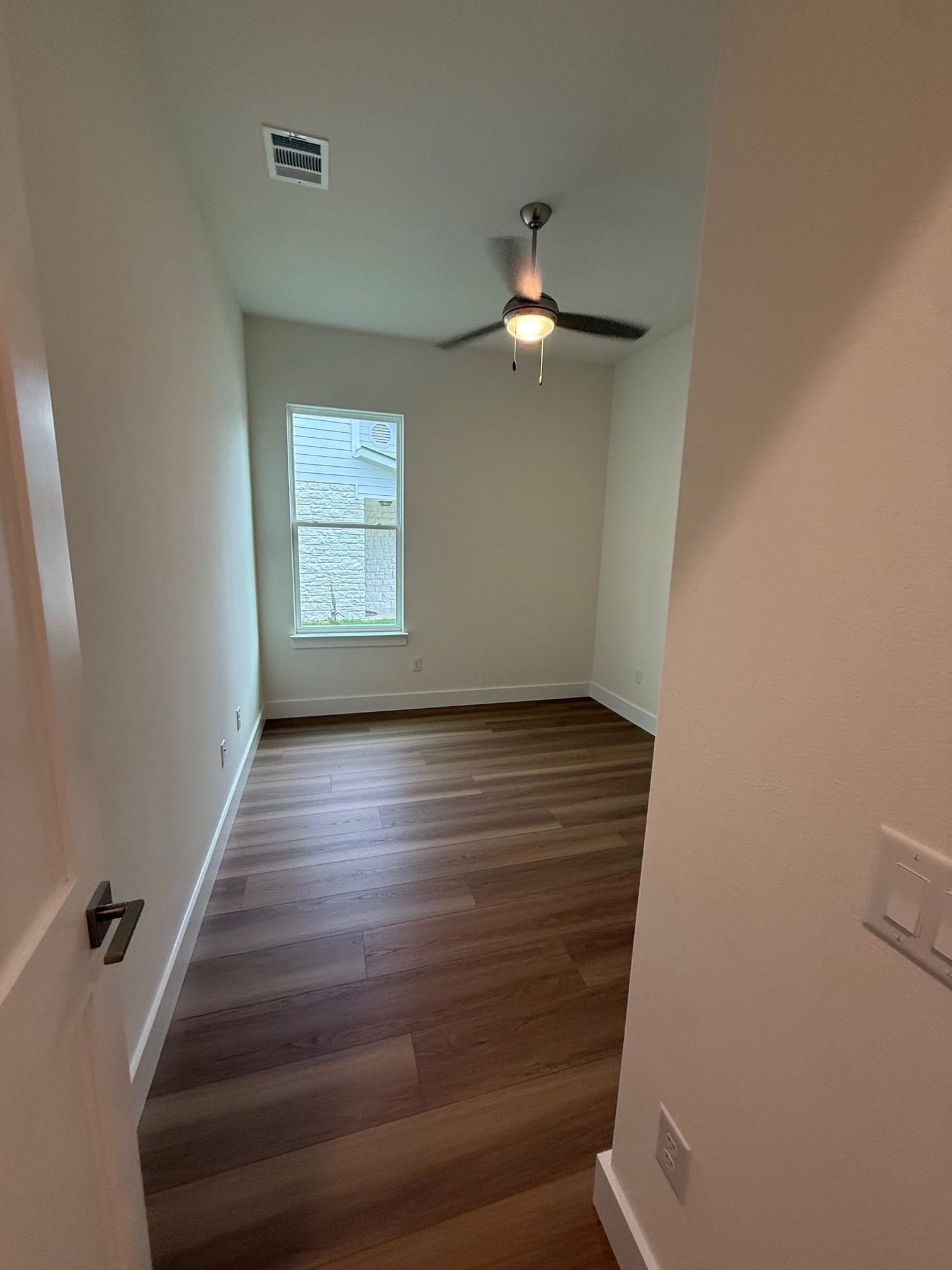 110 Firestone Place Meadowlakes, TX 78654 - Photo 13 of 18 Room featuring wood-finish flooring, a ceiling fan with integrated lighting, and a single window with white trim