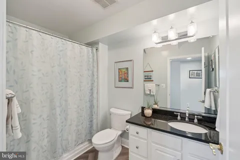 a bathroom with a granite countertop sink a toilet and a mirror