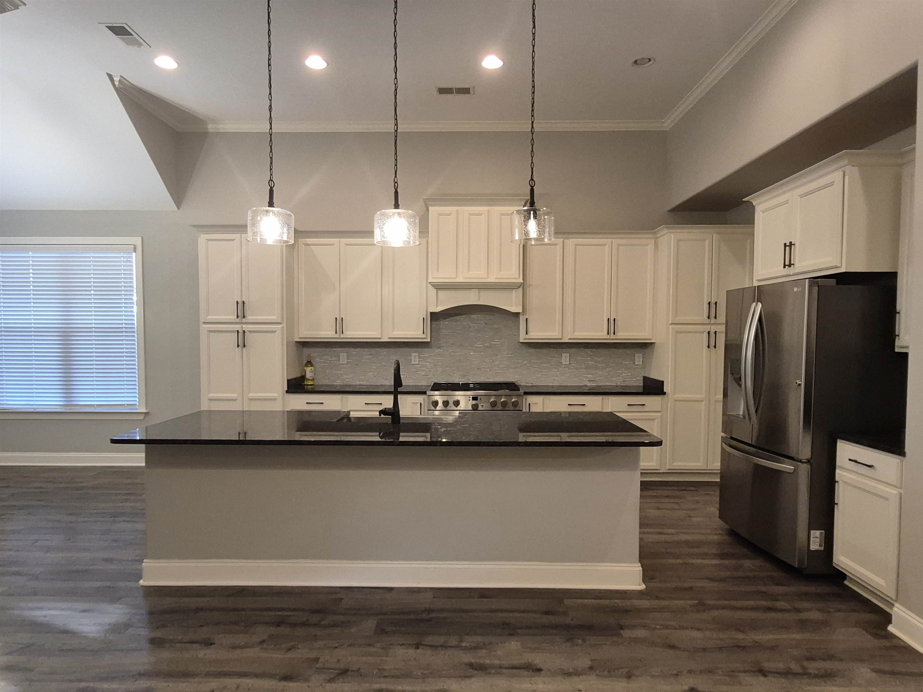 5120 Moudry Lane Lakeland, TN 38002 - Photo 8 of 34 Kitchen featuring stainless steel fridge, range, dark countertops, ornamental molding, and white cabinets