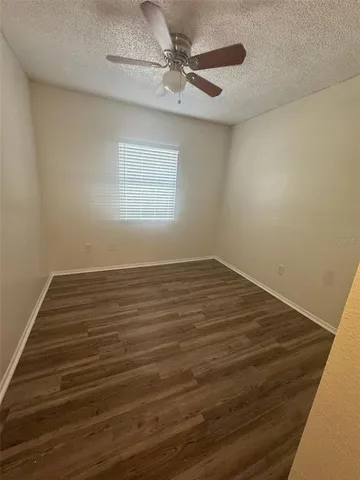 an empty room with wooden floor fan and windows
