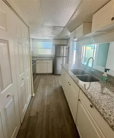 a kitchen with granite countertop a sink a counter top space stainless steel appliances and cabinets