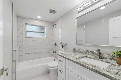 a bathroom with a granite countertop sink toilet and mirror