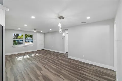 a view of an empty room with wooden floor and window