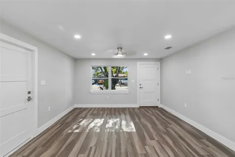 a view of an empty room with wooden floor and a window
