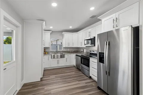 a view of kitchen with kitchen island wooden floor appliances and cabinets