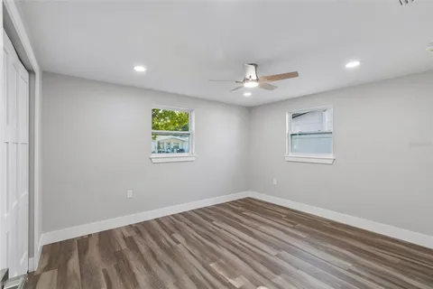 a view of an empty room with window and wooden floor