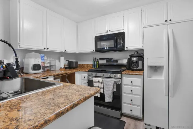 a kitchen with granite countertop white cabinets and stainless steel appliances
