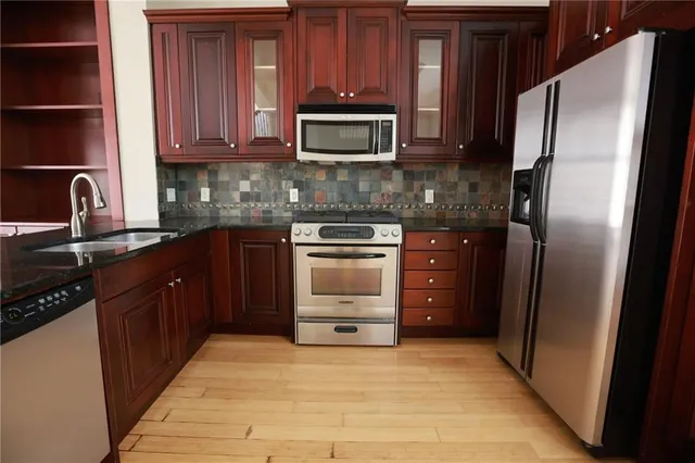 a kitchen with stainless steel appliances granite countertop a stove a sink and a refrigerator