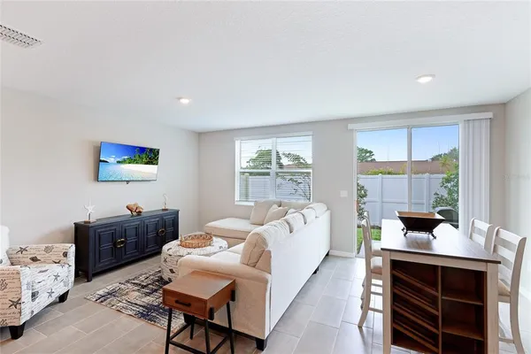 a living room with furniture a flat screen tv and large window