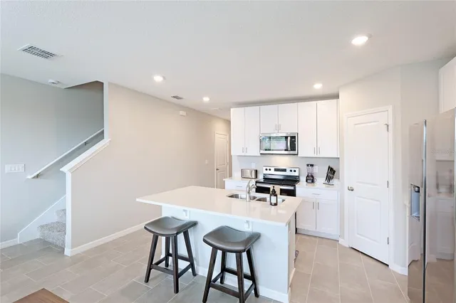 a kitchen with stainless steel appliances kitchen island granite countertop a refrigerator and a stove top oven