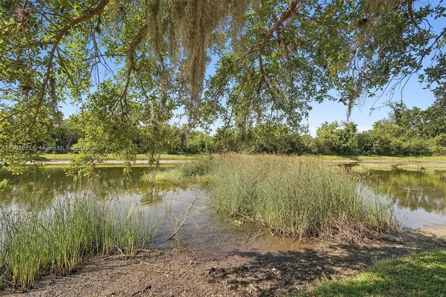 a view of a white house with a fountain and potted plants