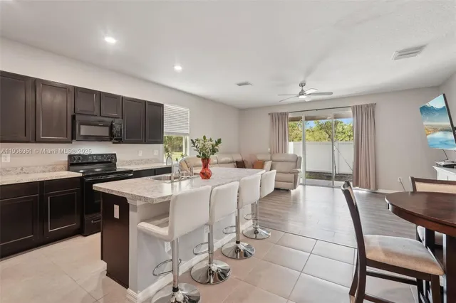 a kitchen with granite countertop a refrigerator a sink a stove a dining table and chairs