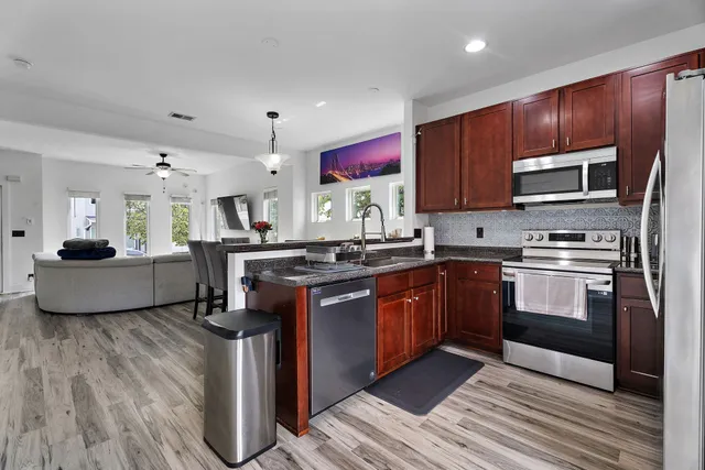 a kitchen with kitchen island granite countertop wooden cabinets stainless steel appliances and a window