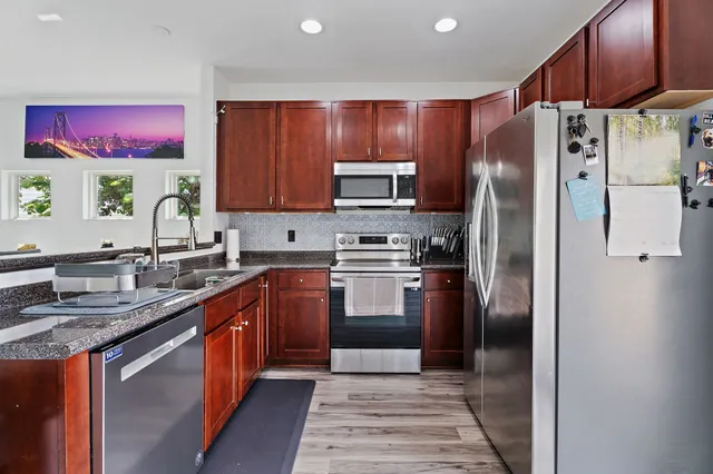 a kitchen with stainless steel appliances granite countertop a refrigerator stove top oven and sink