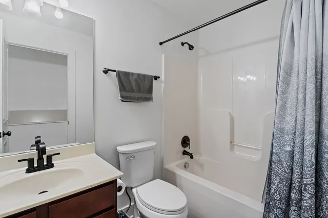 a bathroom with a sink a toilet a mirror a vanity and shower