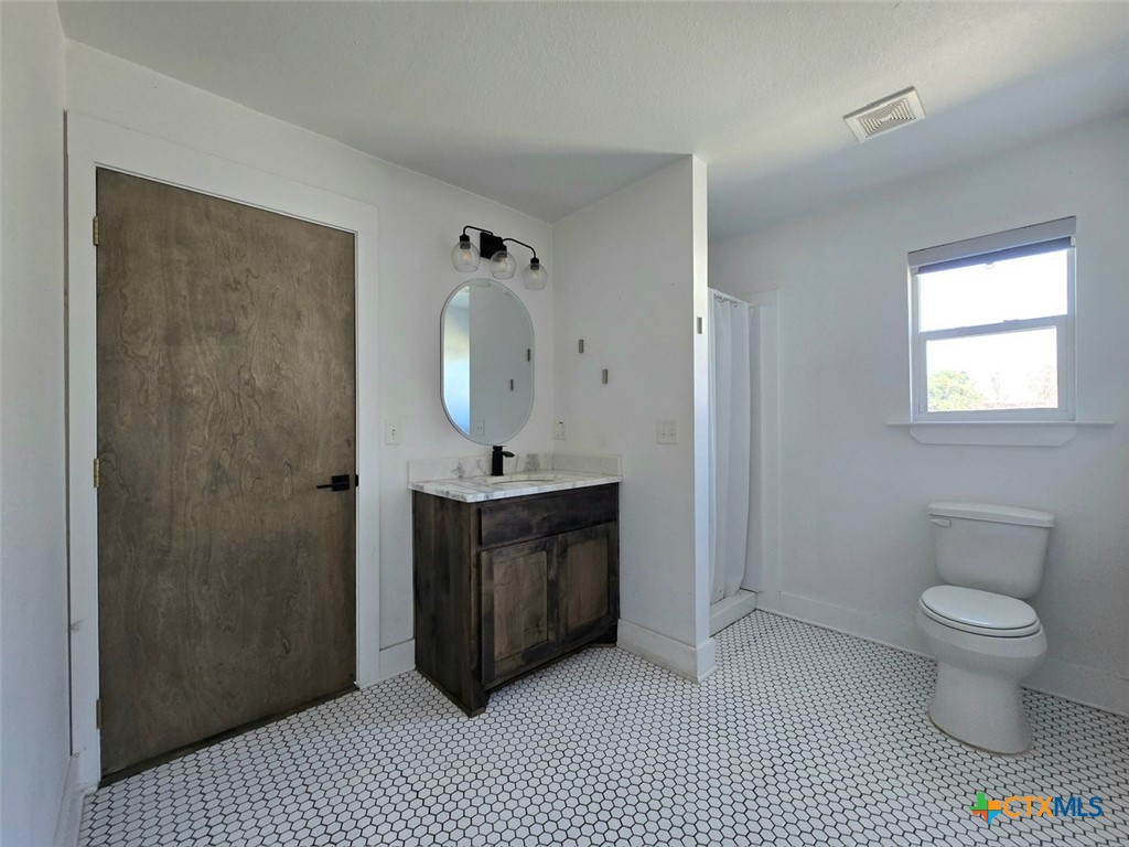 1005 Bridge Street Lampasas, TX 76550 - Photo 19 of 29 a bathroom with a sink a toilet and a mirror