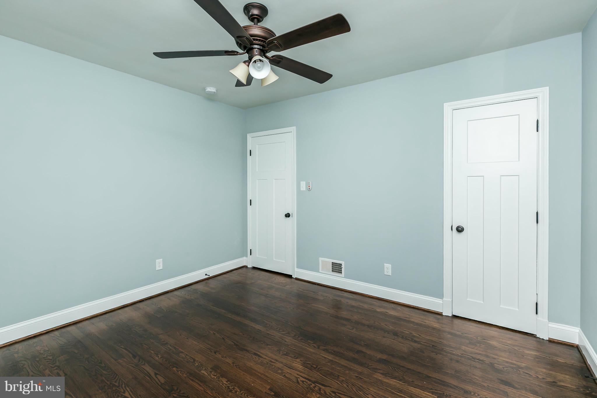 5504 Catalpha Road Baltimore, MD 21214 - Photo 19 of 28 an empty room with wooden floor and ceiling fan