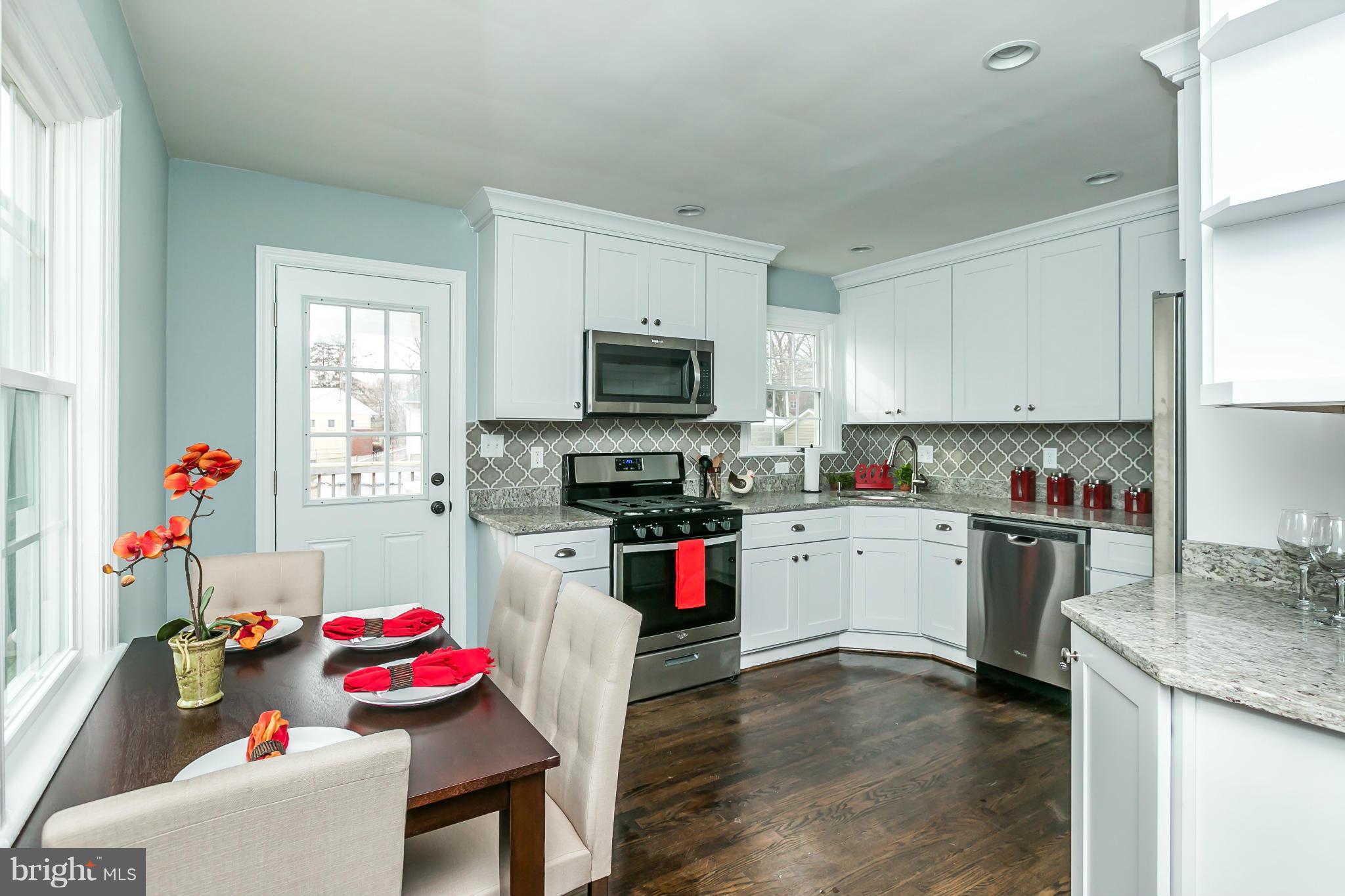 5504 Catalpha Road Baltimore, MD 21214 - Photo 6 of 28 a kitchen with a stove a sink dishwasher and a refrigerator with wooden floor
