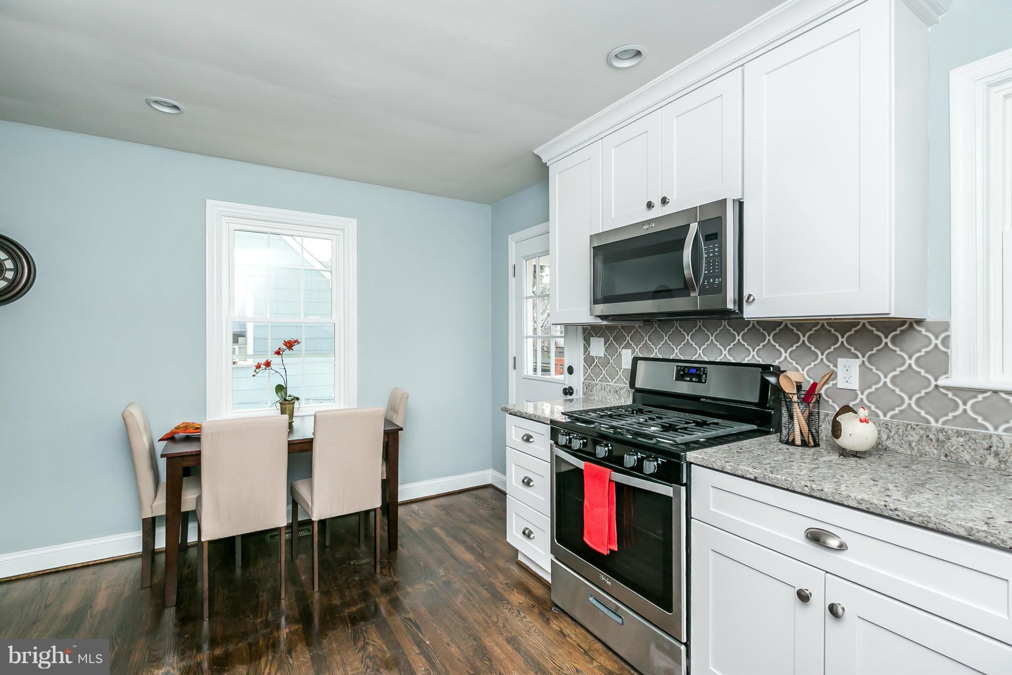 5504 Catalpha Road Baltimore, MD 21214 - Photo 9 of 28 a kitchen with stainless steel appliances kitchen island granite countertop a stove a sink and a microwave