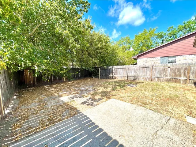 a view of a backyard with large trees and wooden fence