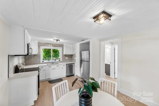 a kitchen with a refrigerator a sink dishwasher a dining table and chairs with wooden floor