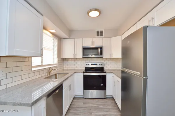 a kitchen with stainless steel appliances granite countertop a refrigerator stove a sink and dishwasher with wooden floor