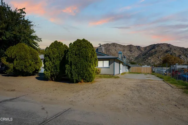 a view of a house with a yard and a large tree