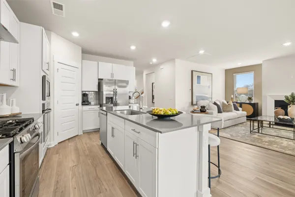 a kitchen that has a lot of white cabinets and stainless steel appliances