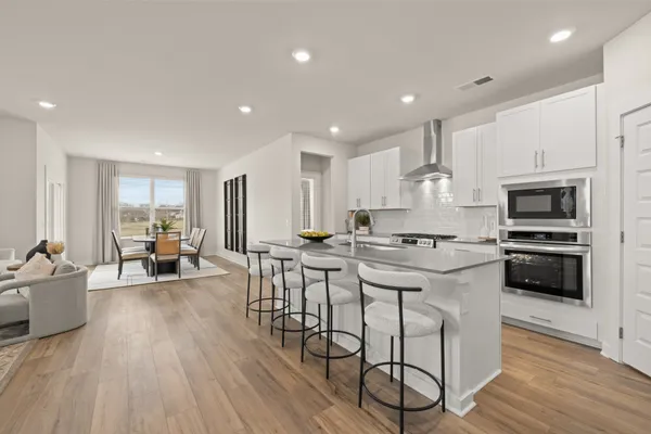 a kitchen with stainless steel appliances granite countertop a stove a refrigerator a kitchen island with a dining table and chairs with wooden floor