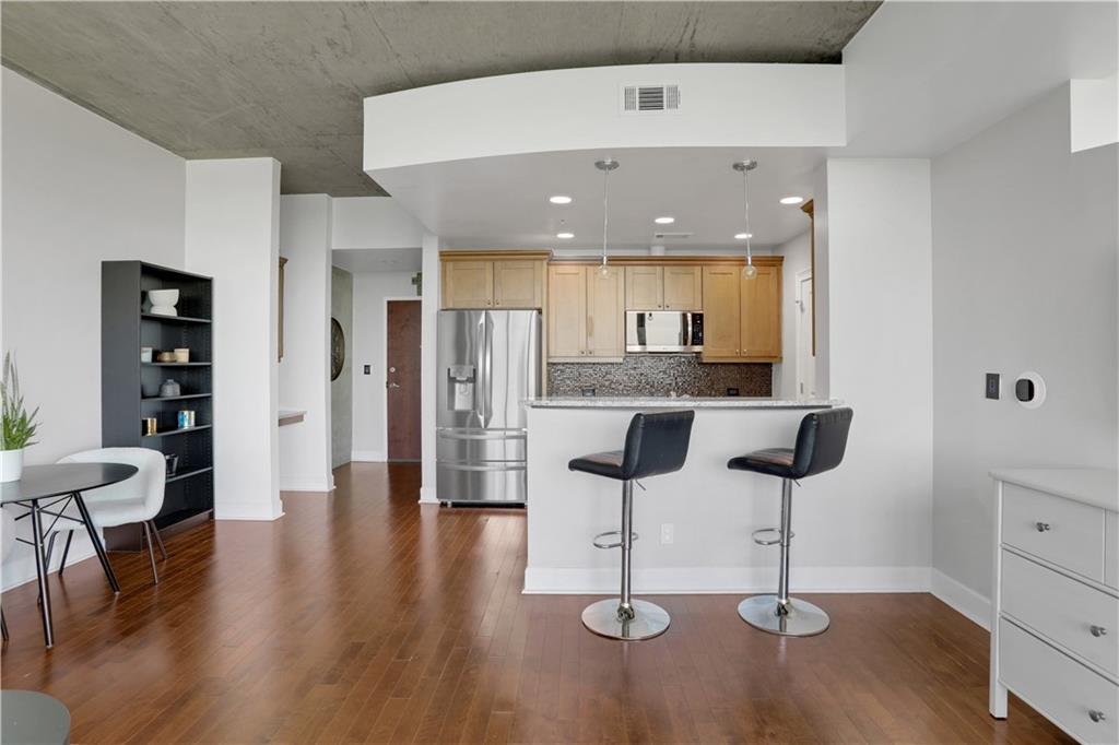 3300 Windy Ridge Parkway Southeast, Unit 1603 Atlanta, GA 30339 - Photo 4 of 36 a kitchen with stainless steel appliances kitchen island granite countertop a table chairs and a refrigerator