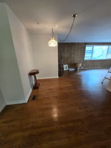 a view of empty room with wooden floor and window