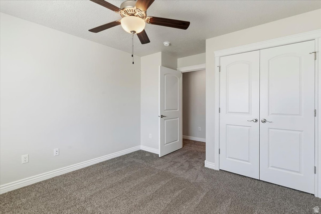 2028 West Grace Way Layton, UT 84041 - Photo 21 of 36 Unfurnished bedroom with dark colored carpet, a closet, a ceiling fan, and a textured ceiling
