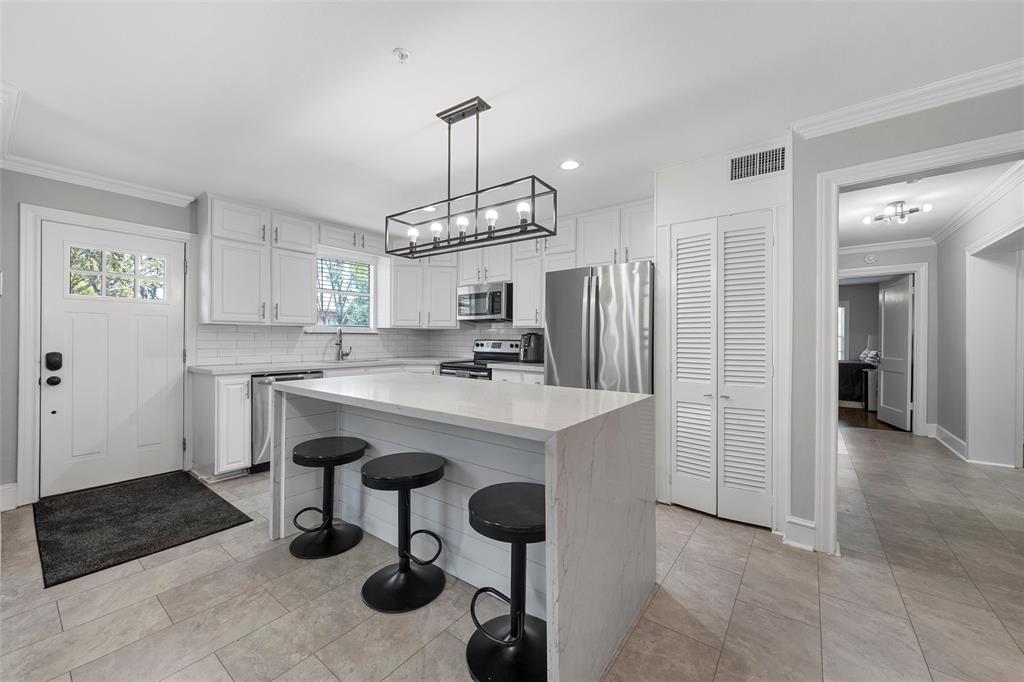 1500 South 10th Street Waco, TX 76706 - Photo 10 of 25 Kitchen with crown molding, a kitchen breakfast bar, white cabinetry, stainless steel appliances, and a center island