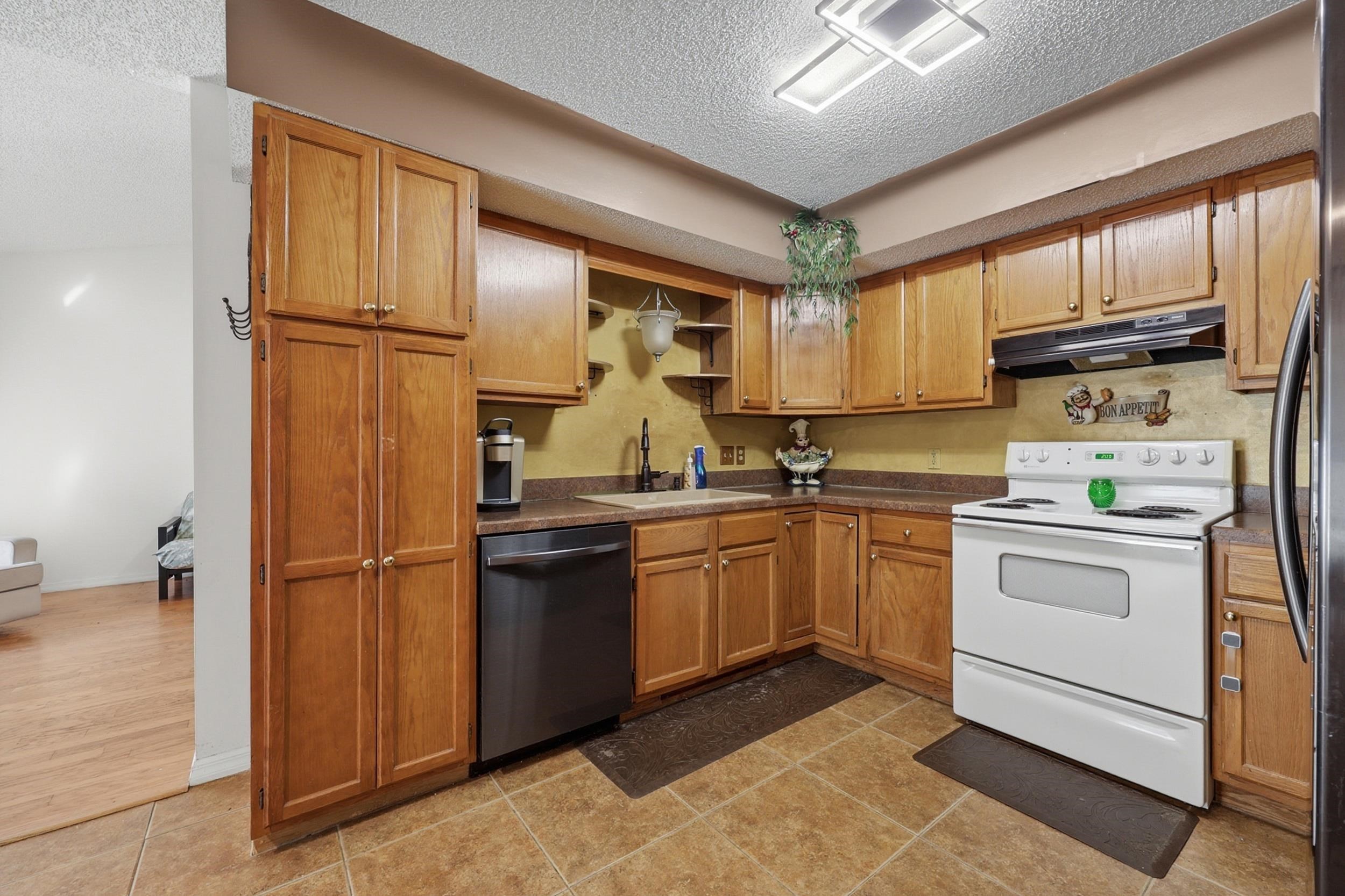5296 Timucua Circle St. Augustine, FL 32086 - Photo 13 of 65 Kitchen featuring stainless steel appliances, a textured ceiling, dark countertops, light tile patterned floors, and wood finish cabinetry