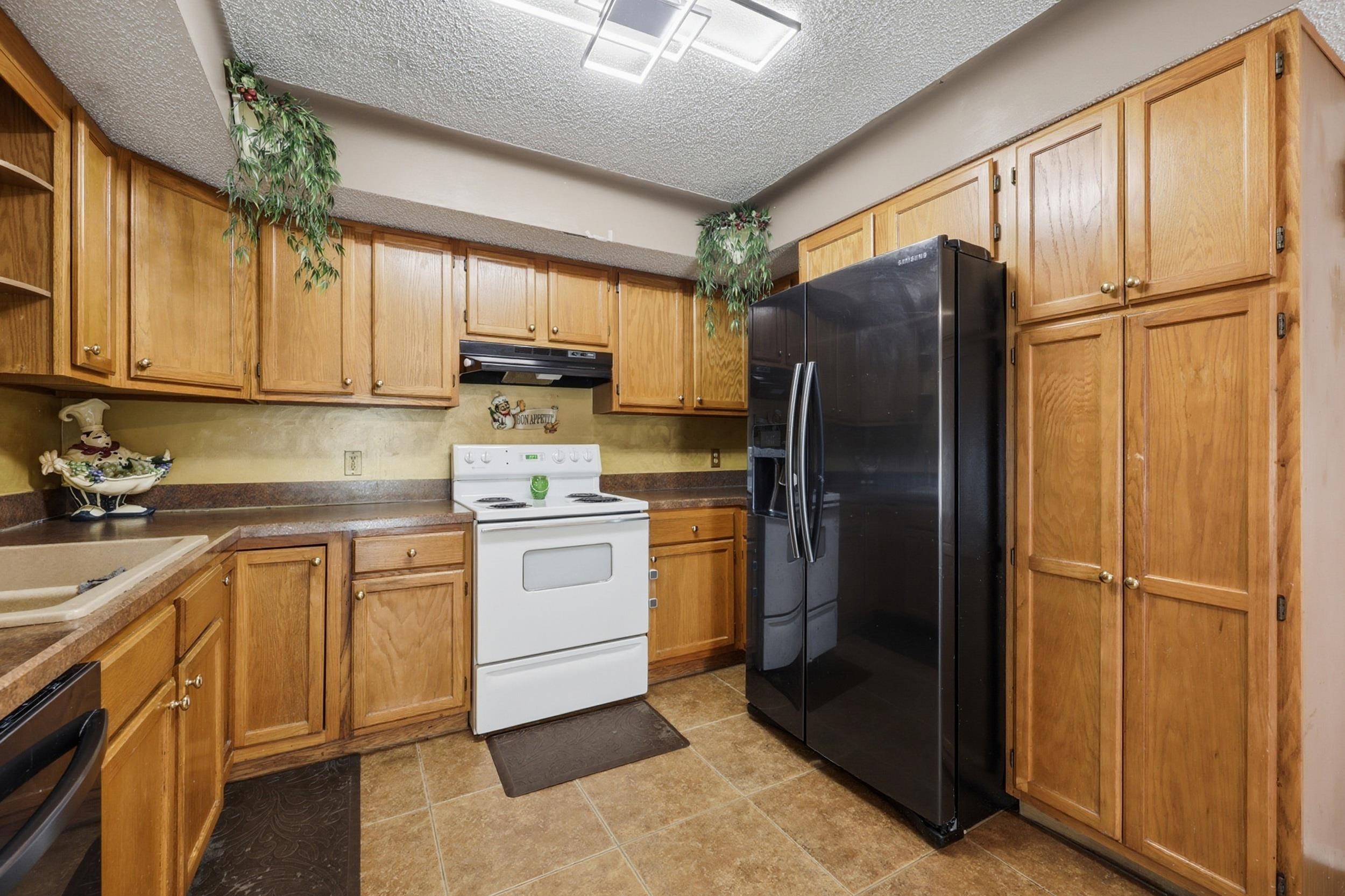 5296 Timucua Circle St. Augustine, FL 32086 - Photo 14 of 65 Kitchen featuring black appliances, a textured ceiling, wood finish cabinets, open shelves, and dark countertops