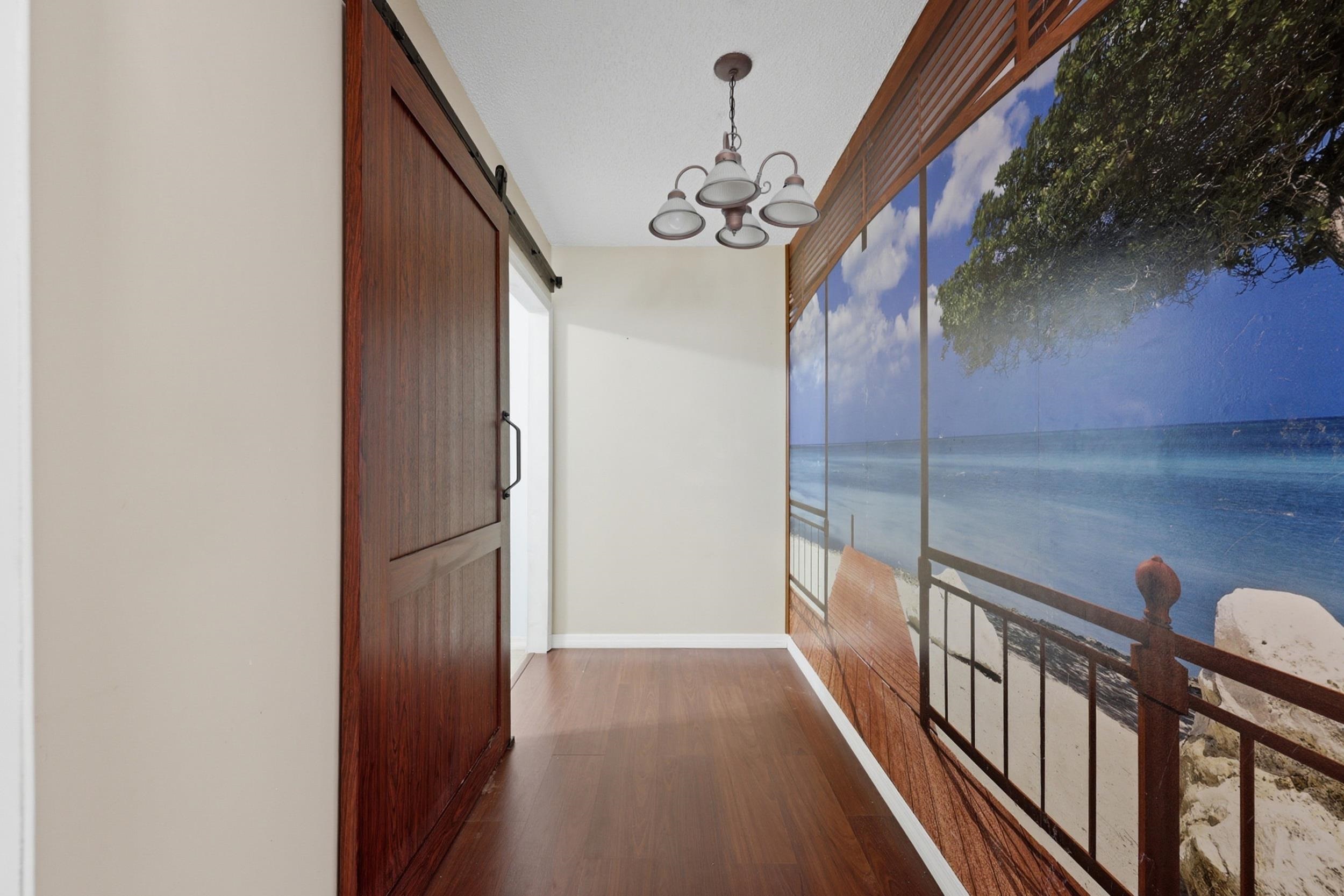5296 Timucua Circle St. Augustine, FL 32086 - Photo 26 of 65 Hall featuring a barn door, dark wood-style floors, a chandelier, and view of water and beach