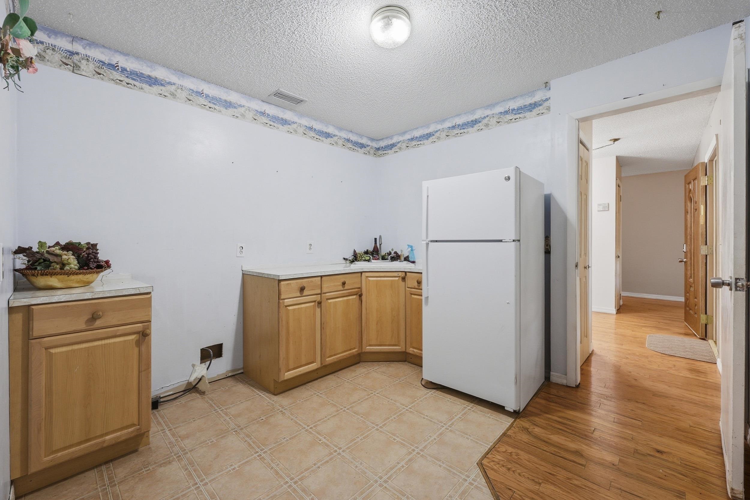 5296 Timucua Circle St. Augustine, FL 32086 - Photo 28 of 65 Kitchen featuring freestanding refrigerator, light countertops, a textured ceiling, and light wood-style flooring
