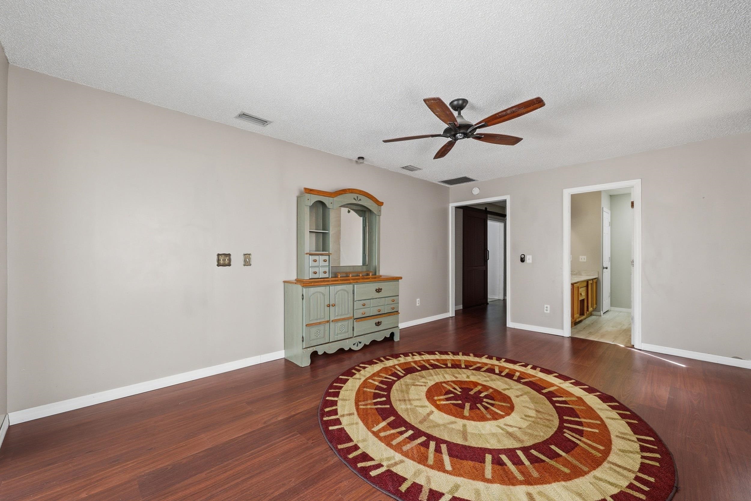 5296 Timucua Circle St. Augustine, FL 32086 - Photo 29 of 65 Bedroom featuring a ceiling fan, dark wood-type flooring, ensuite bathroom, and a textured ceiling